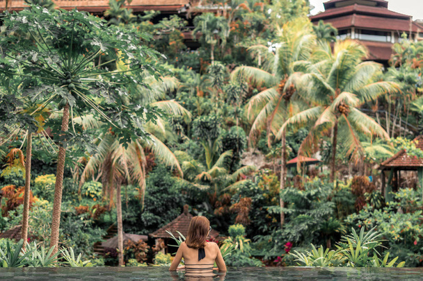 Щасливі молоду жінку в тропічних пейзажний басейн. Розкішний курорт на острові Балі. - Фото, зображення