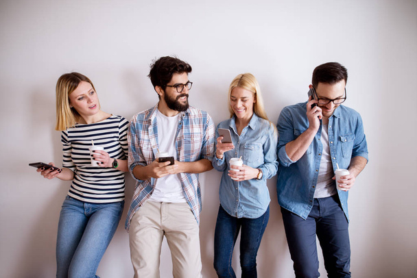 group of young happy coworkers having fun at break while drinking coffee and using gadgets - 写真・画像