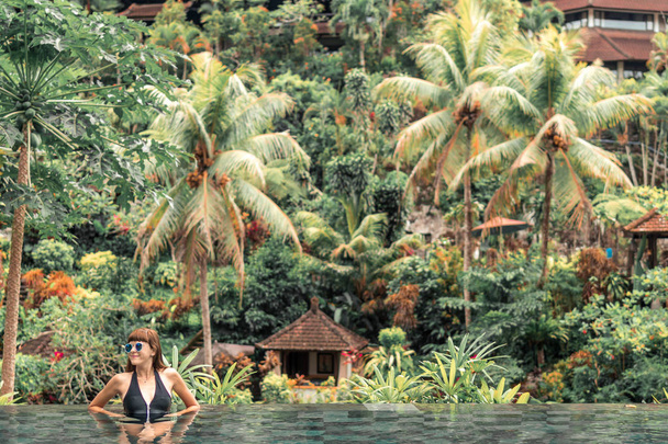 Gelukkig jonge vrouw in een tropische infinity pool. Luxeresort op het eiland Bali. - Foto, afbeelding