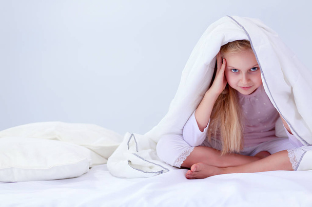 Smiling little girl in the bed under cover - Foto, imagen