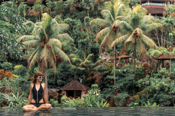 Joyeux jeune femme dans une piscine tropicale à débordement. Resort de luxe sur l'île de Bali
. - Photo, image