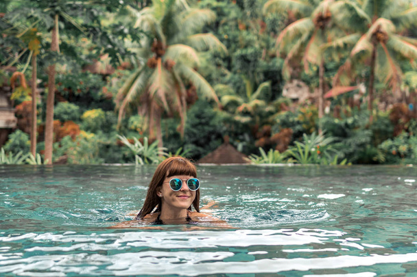 Szczęśliwa młoda kobieta w tropikalny basen. Luksusowy ośrodek na wyspie Bali. - Zdjęcie, obraz