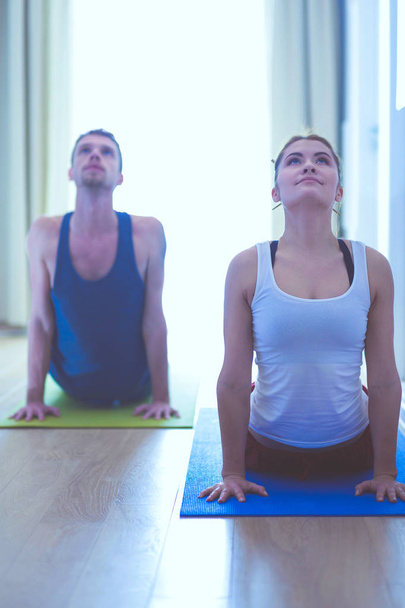 Jeune couple en bonne santé en position de yoga sur fond blanc
 - Photo, image