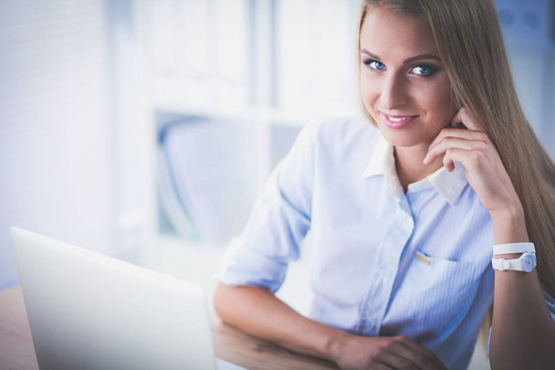 Attractive businesswoman sitting on a desk with laptop in the office - Fotoğraf, Görsel