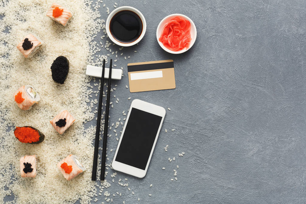 Sushi roll i gunkan w pobliżu telefonu i karty kredytowej - Zdjęcie, obraz