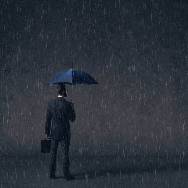 Businessman with umbrella standing under the rain. Dark, dramatic background. Business, failure, crisis, concept.  - Fotó, kép
