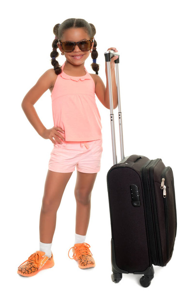 Cute multiracial small girl carrying a travel suitcase and smiling - Valokuva, kuva