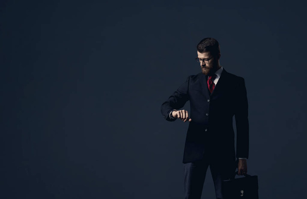 Businessman with briefcase standing over black dramatic background. Business and office, concept. - Fotografie, Obrázek