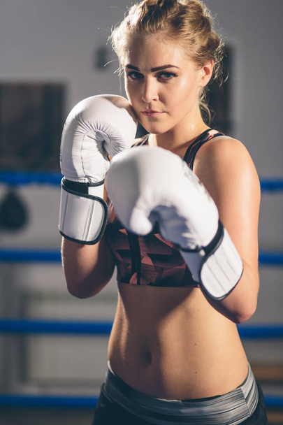 Female Boxer wearing gloves posing in boxing studio - Zdjęcie, obraz