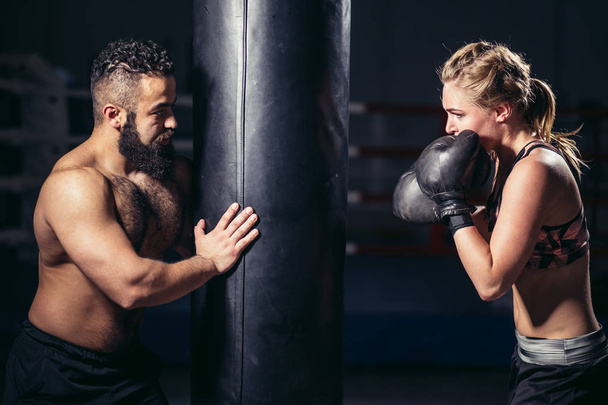 woman working out with boxing gloves and punching bag with her trainer. - Фото, зображення