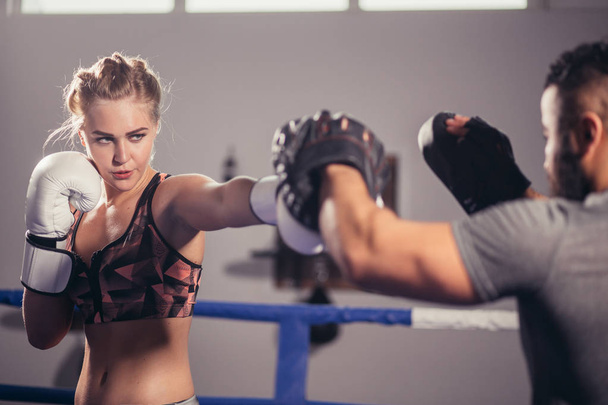 Boxing girl training on boxing mitts held by a master boxer - Valokuva, kuva