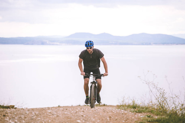 テーマ観光やマウンテン バイクでサイクリングします。男に乗ってヘルメットやスポーツウェアのコスタ ・ ブラバの海岸にスペインの地中海の背景の岩、岩道路上り - 写真・画像