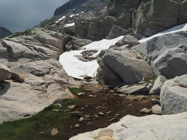 βουνό χιόνι γλώσσα με ογκόλιθους νερό ρεύμα και πράσινο γρασίδι - Φωτογραφία, εικόνα