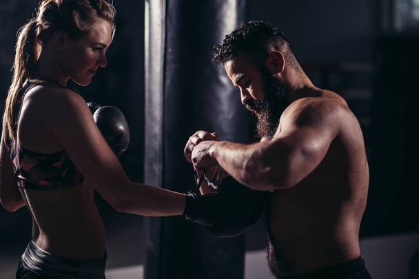 woman working out with boxing gloves and punching bag with her trainer. - Photo, image
