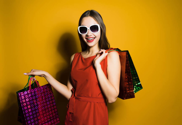 happy woman in a beautiful red dress holding shopping bags - Фото, зображення