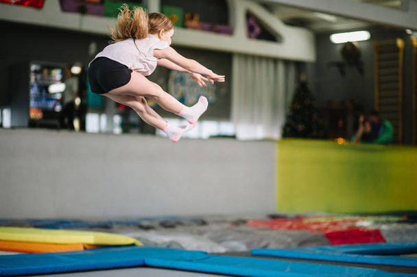 Girl jumping high in striped tights on trampoline. - Foto, Imagen