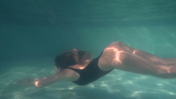 Žena v modrých plavkách plavání pod vodou v pomalém pohybu - Záběry, video