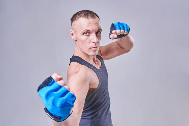A handsome sports man stands in a fighting pose, in gloves - Photo, Image