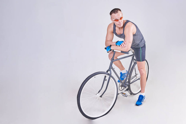 A handsome sports man sits on a Bicycle - Foto, Bild