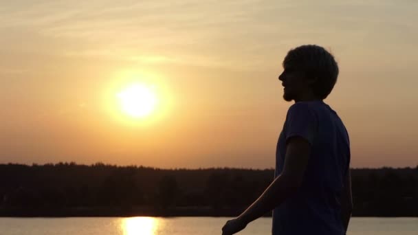 Junger Mann hebt glücklich seine Siegerschale an einem See in Slo-mo - Filmmaterial, Video