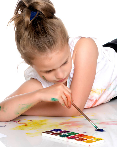 A little girl paints with paint and brush. - Fotó, kép