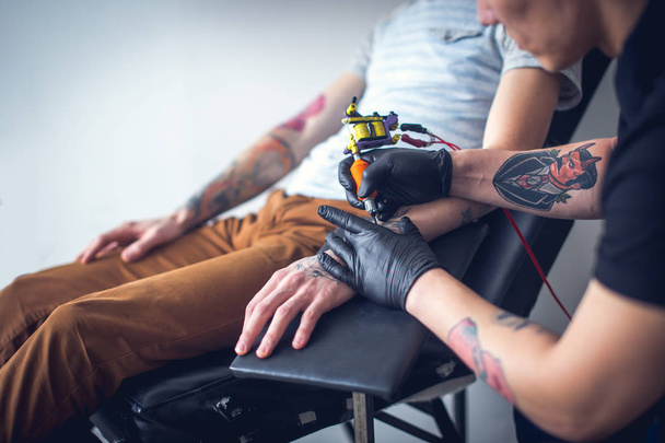 Master tattoo artist in gloves makes tattoo - Foto, afbeelding