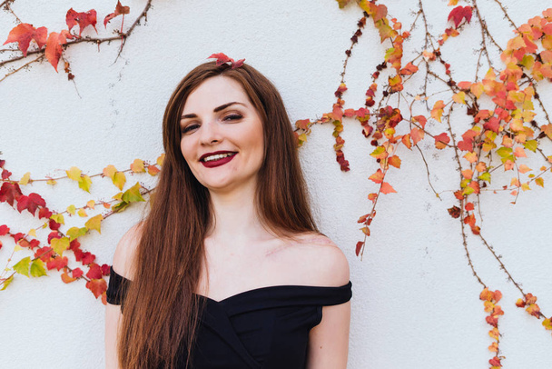 luxurious attractive beautiful woman in black dress smiling posing against white wall - 写真・画像