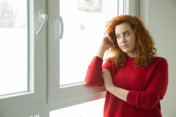 Red-haired girl by the window - Fotografie, Obrázek