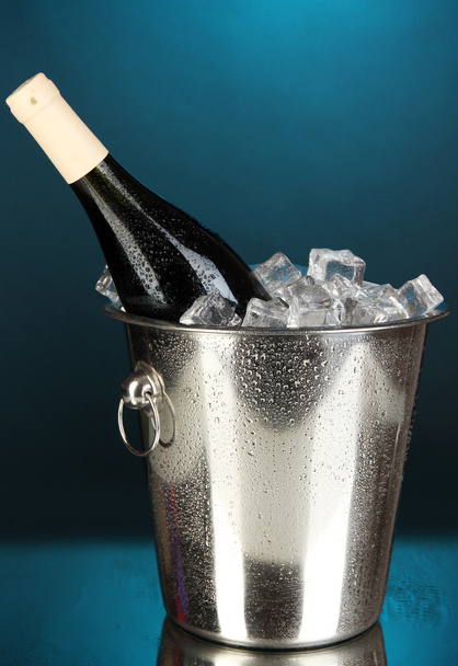Bottle of wine in ice bucket on darck blue background - Fotoğraf, Görsel