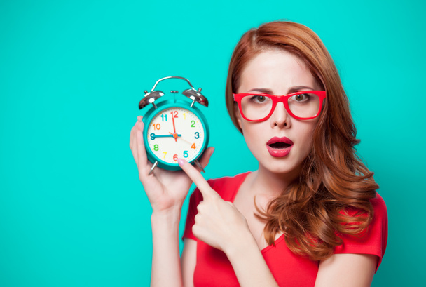 Young beautfiul redhead girl with alarm clock on minty background - Фото, изображение