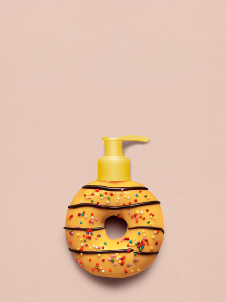 Creative still life of a tasty sweet yellow donut with a cosmetic pump dispenser on pink background. - Φωτογραφία, εικόνα