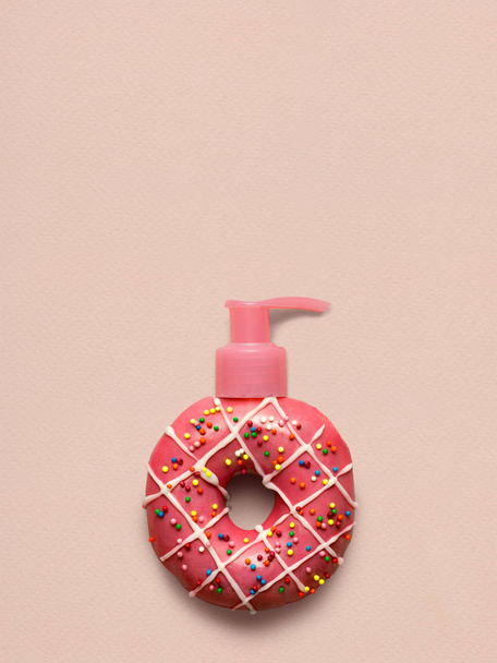 Creative still life of a tasty sweet strawberry donut with a cosmetic pump dispenser on pink background. - Φωτογραφία, εικόνα