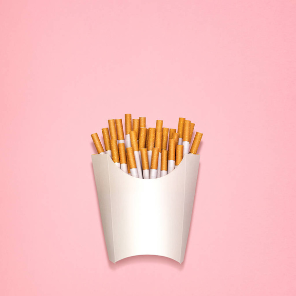 Conceptual still life of cigarettes, packed as fried potatoes in a paper box. - Photo, Image
