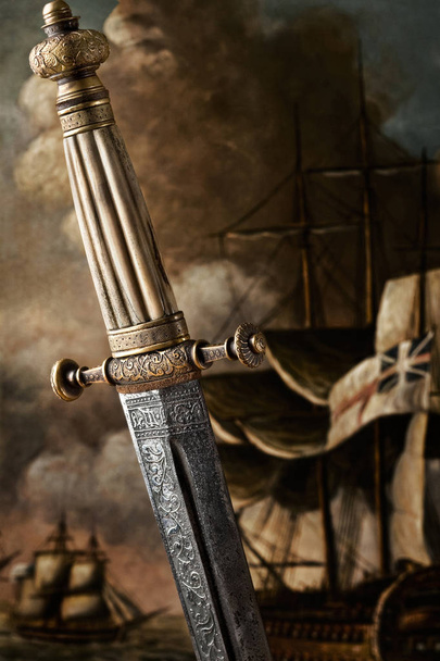 A close-up of an ancient carved sword against painted background. A closeup view of the handle and the blade design of a Slavic dagger from 19th century. - Photo, Image