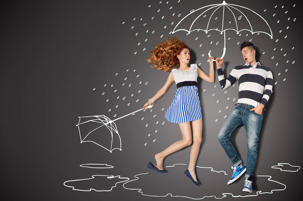 Happy valentines love story concept of a romantic couple in the rain against chalk drawings background. - Photo, Image