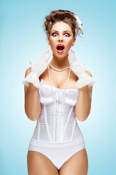 The retro photo of a shocked and surprised bride with stylish makeup in a vintage corset showing strong emotions. - Foto, afbeelding