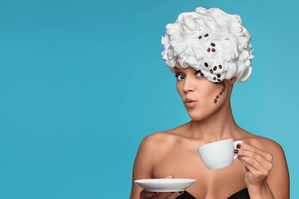 A young lady in a whipped cream on her head with a coffee cup. - Zdjęcie, obraz