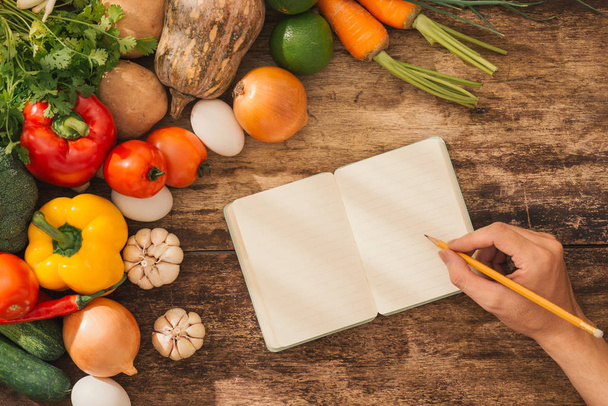 Libro de cocina. Verduras frescas alrededor de cuaderno abierto sobre fondo rústico
.  - Foto, Imagen