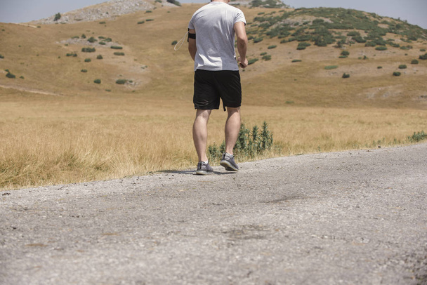 Male runner running on mountain under the sun - healthy lifestyle concept - Photo, Image