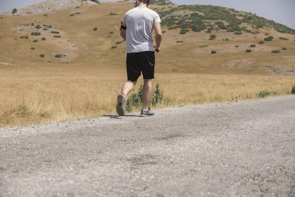 Erkek koşucu güneşin altında dağda koşuyor - sağlıklı yaşam tarzı kavramı - Fotoğraf, Görsel