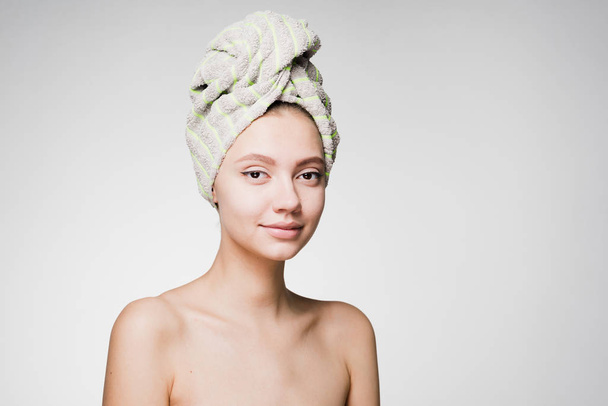 young beautiful girl with a towel on her head looking at the camera, thinking about beauty - Φωτογραφία, εικόνα
