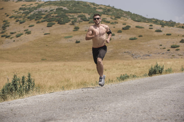 mężczyzna biegacz działa na górze pod słońcem - zdrowy styl życia koncepcja - Zdjęcie, obraz