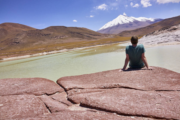 Homem sentado nas Piedras Rojas no Chile e olhando para a Cordilheira dos Andes
 - Foto, Imagem