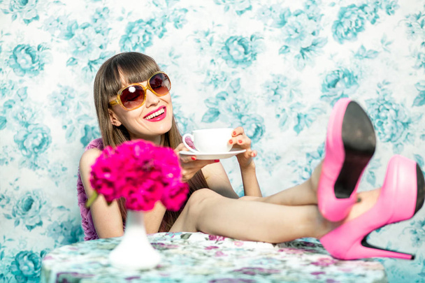 Krásná dívka v růžových šatech květinové vinobraní modré pozadí. Umělecké dílo romantické ženy. Pěkně řízení jarní žena u čaje nebo kávy - Fotografie, Obrázek