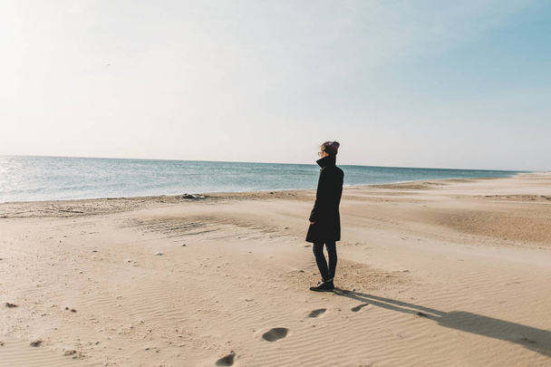Woman walking on sandy shore near the sea.  - Fotó, kép