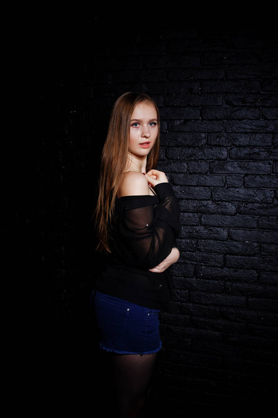 Studio shot of brunette girl in black blouse with bra and shorts - Фото, зображення