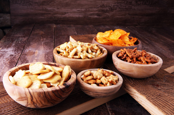 Snacks salados. Pretzels, papas fritas, galletas en cuencos de madera
 - Foto, imagen