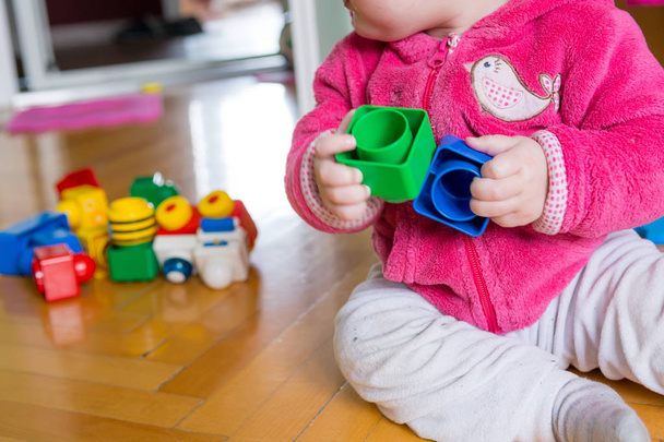 Baby playing with colorful bricks on wooden floor. - Φωτογραφία, εικόνα