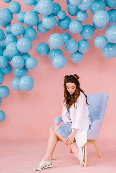 Beautiful girl in a blue dress in a pink room with blue balls an - Fotó, kép