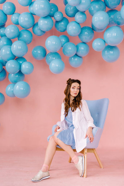 Beautiful girl in a blue dress in a pink room with blue balls an - Фото, изображение